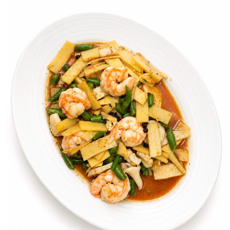 Shrimp stir-fry with bamboo shoots, green beans, mushrooms, and peppers in a savory reddish sauce on a white platter.