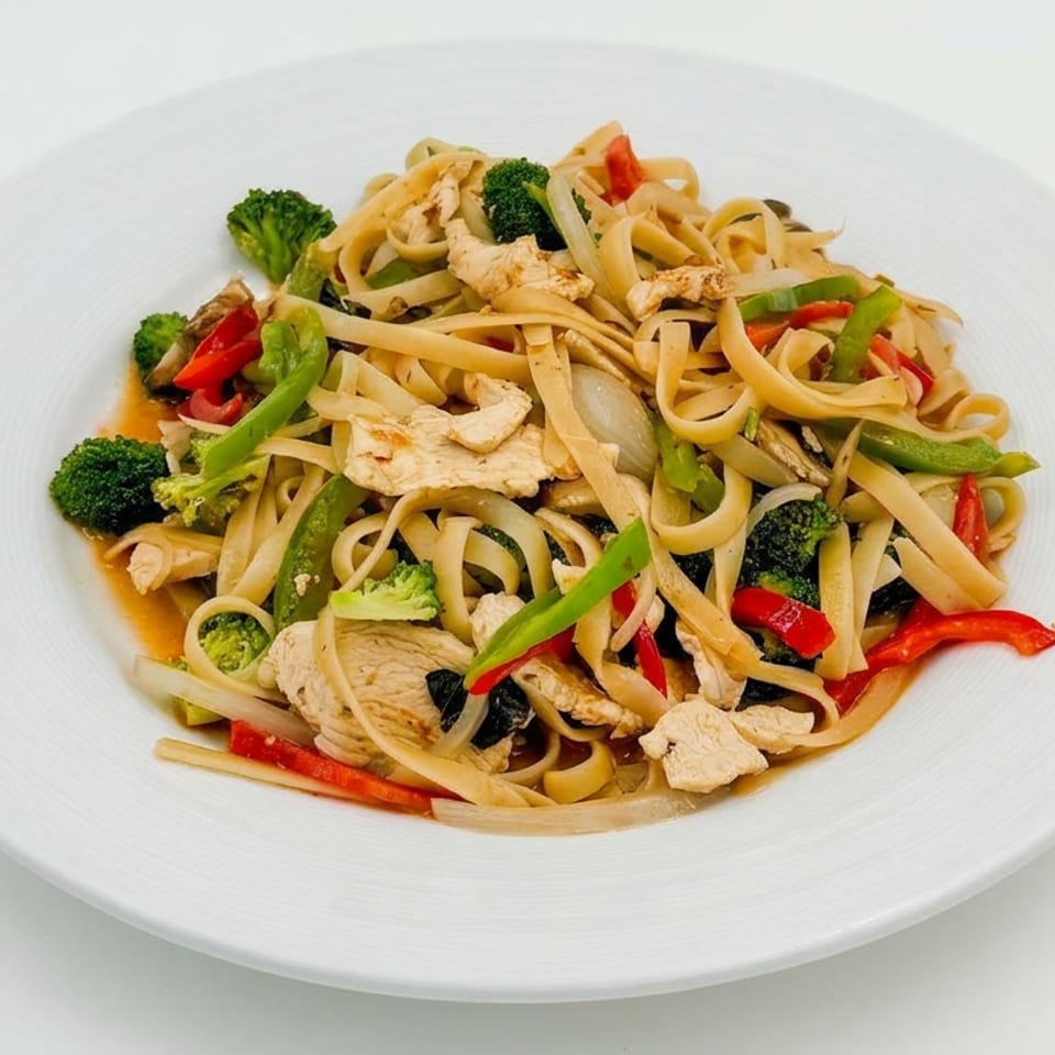 Stir-fried flat noodles with sliced chicken, broccoli, bell peppers, and onions served on a white plate.
