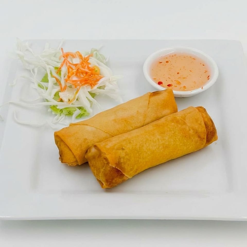 Two golden fried spring rolls served with shredded cabbage, carrots, and a bowl of sweet chili dipping sauce.